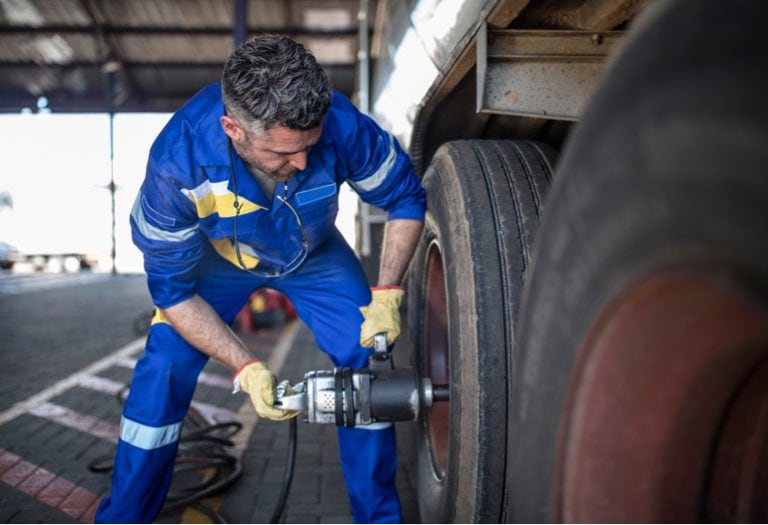 A man tightening lug nuts on a semi