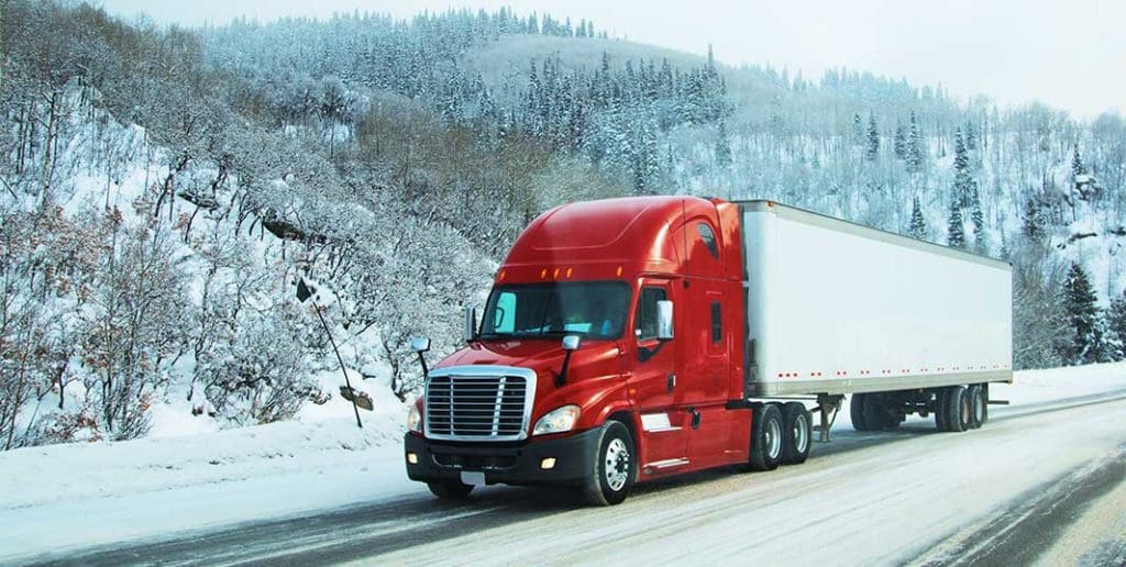 semi driving down a road in the winter