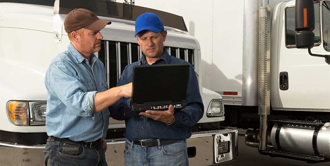 two people looking at a screen in front of a semi