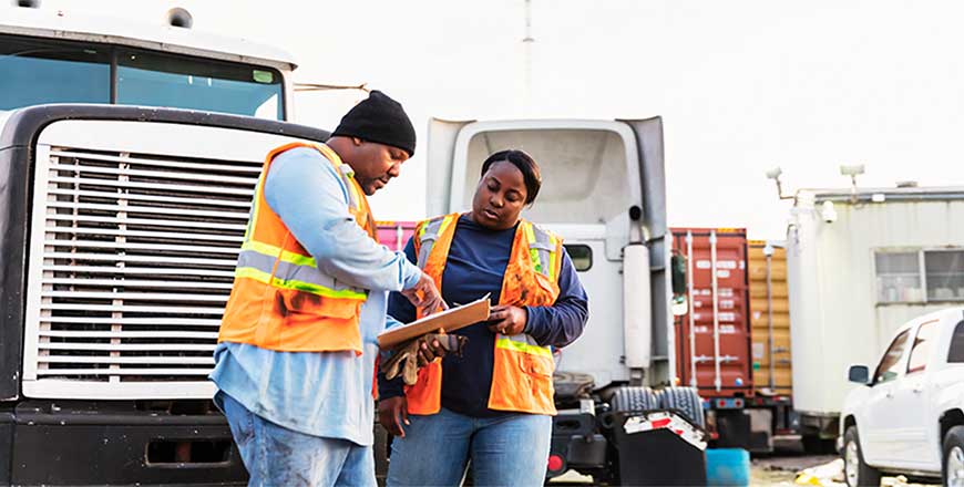 two construction workers looking at a clipboard