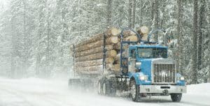 logging truck driving on a snowy street