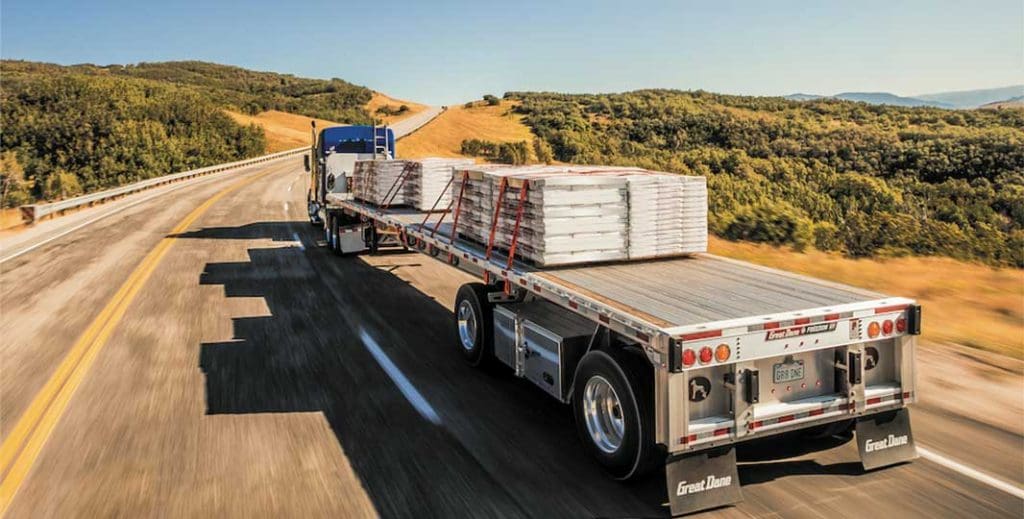 Great Dane flat bed truck pallets driving on an open highway.
